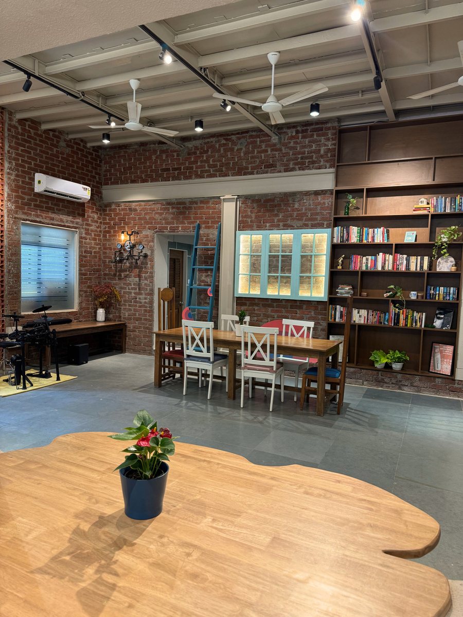 The Gather studio set for a workshop: bookshelves, a long table and a drum kit